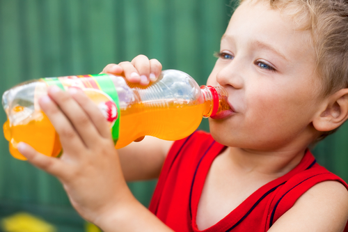 Little boy drinking unhealthy bottled soda
